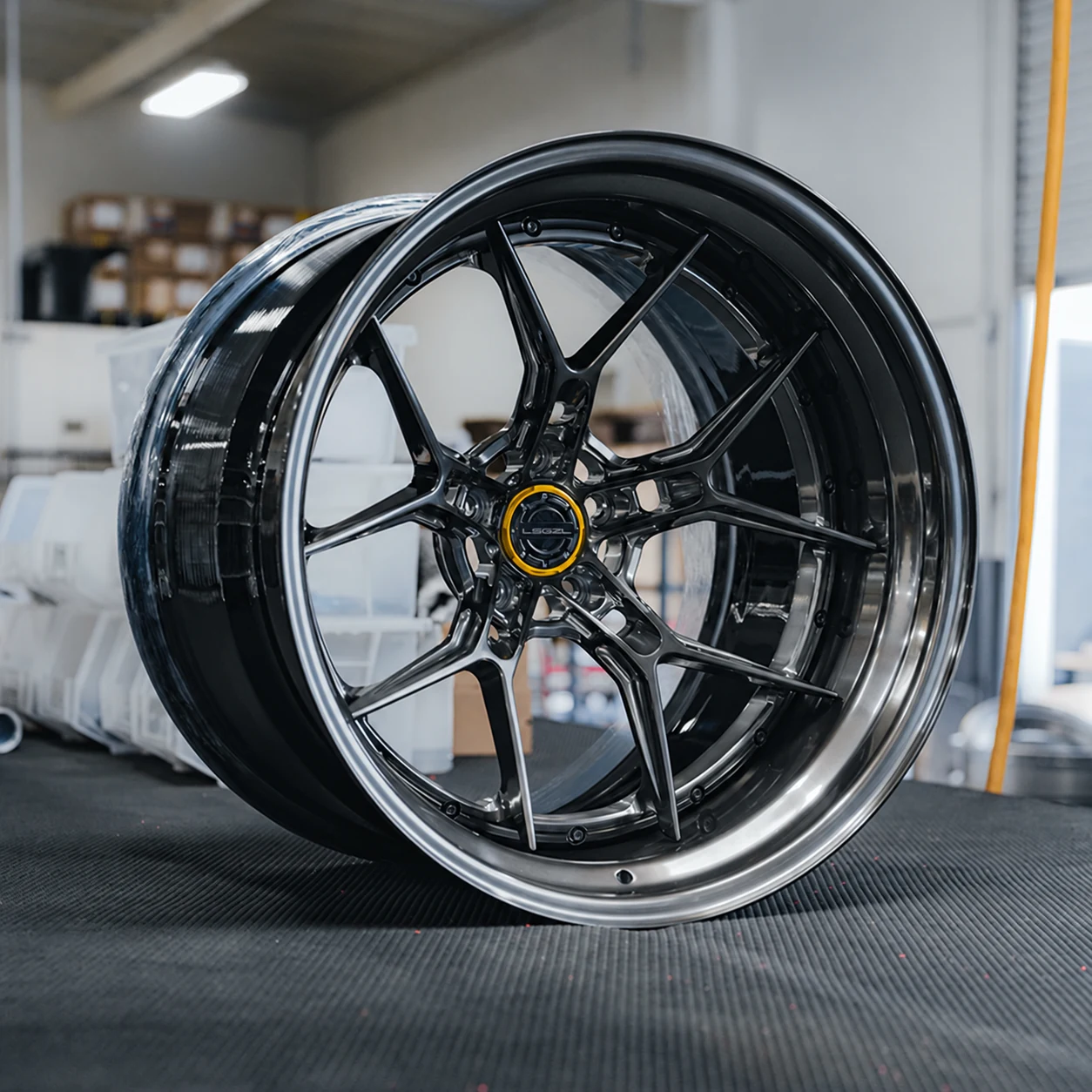 Dark polished split-spoke alloy wheel in a workshop